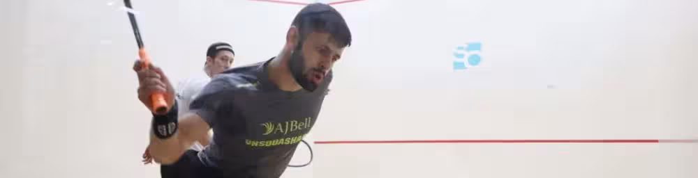 A squash player in the righ-hand back corner ready to play a shot